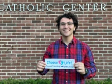 Gabriel Dionisi, a 22-year-old college student who makes pro-life bumper stickers with the goal of spreading the pro-life message and spread awareness to others, displays one of his works.