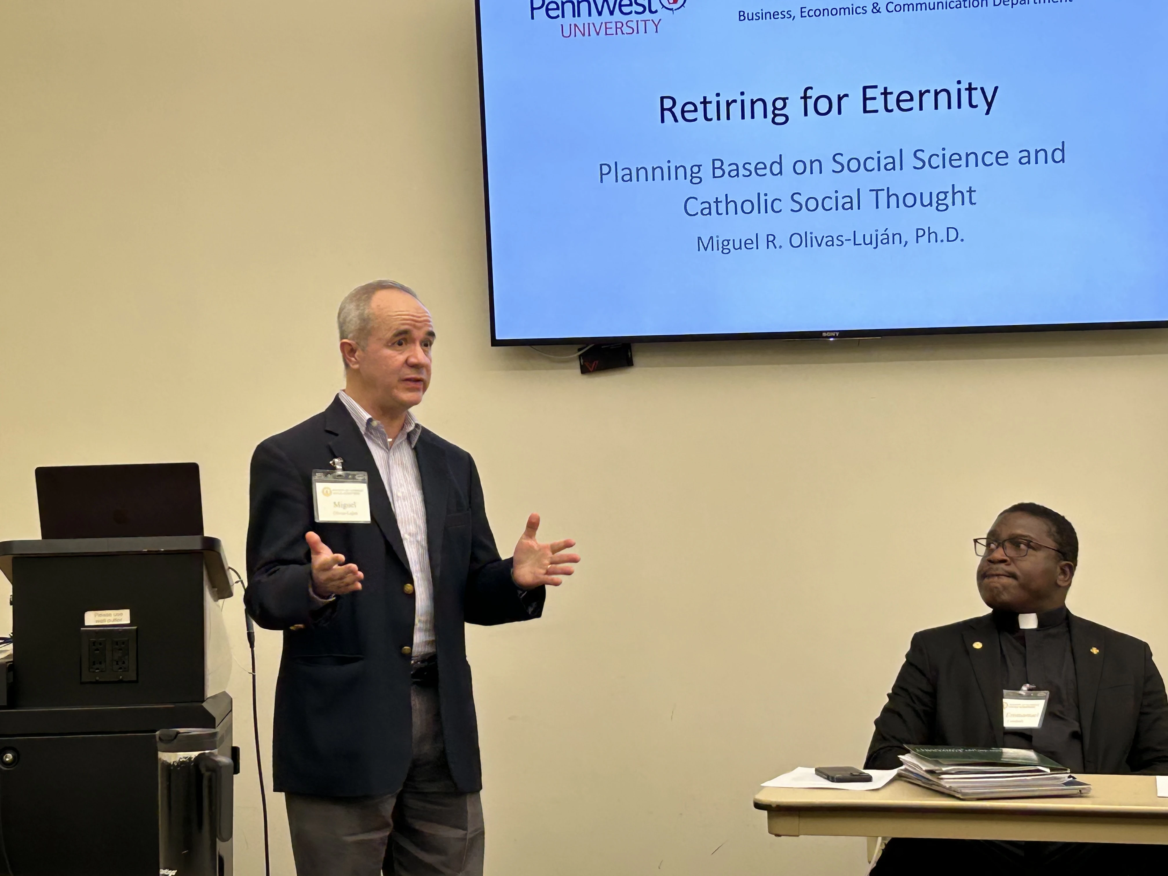 As Father Emmanuel Nanabanyin Conduah (right) looks on, PennWest University Professor Miguel Olivas-Luján (left) delivers his paper “Retiring for Eternity: Planning Based on Social Science and Catholic Social Thought” during the 2025 annual conference of the Society of Catholic Social Scientists at the Franciscan University of Steubenville.?w=200&h=150