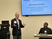 As Father Emmanuel Nanabanyin Conduah (right) looks on, PennWest University Professor Miguel Olivas-Luján (left) delivers his paper “Retiring for Eternity: Planning Based on Social Science and Catholic Social Thought” during the 2025 annual conference of the Society of Catholic Social Scientists at the Franciscan University of Steubenville.