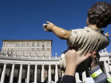 A member of the crowd in St. Peter's Square holds up a baby Jesus figure for a blessing by Pope Francis at his Sunday Angelus Dec. 17, 2023.