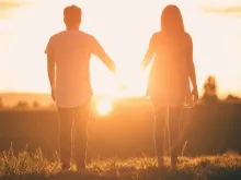 Couple holding hands at sunset. 