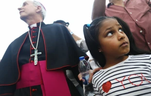 El Paso Bishop Mark Seitz prepares to escort Celsia Palma, 9, from Honduras, before they cross a Port of Entry bridge towards the U.S. on June 27, in Ciudad Juarez, Mexico.   Mario Tama/Getty