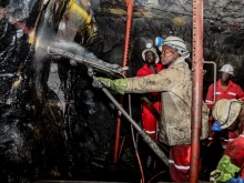 South African platinum and chrome miners drilling holes in rock for blasting.