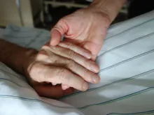 Nurse holding hand of patient. Stock photo via Shutterstock.