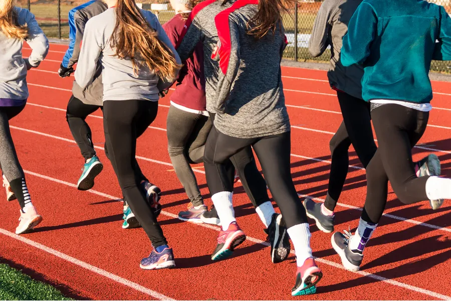 A group of high school girls running on a track. Via Shutterstock?w=200&h=150