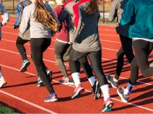 A group of high school girls running on a track. Via Shutterstock