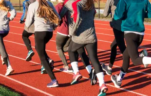 A group of high school girls running on a track. Via Shutterstock 