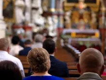 People sitting in pews in church. Stock photo via Shutterstock.