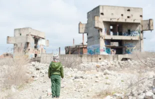 Child standing in front of ruined building in Syria.   Ruslan Shugushev/Shutterstock