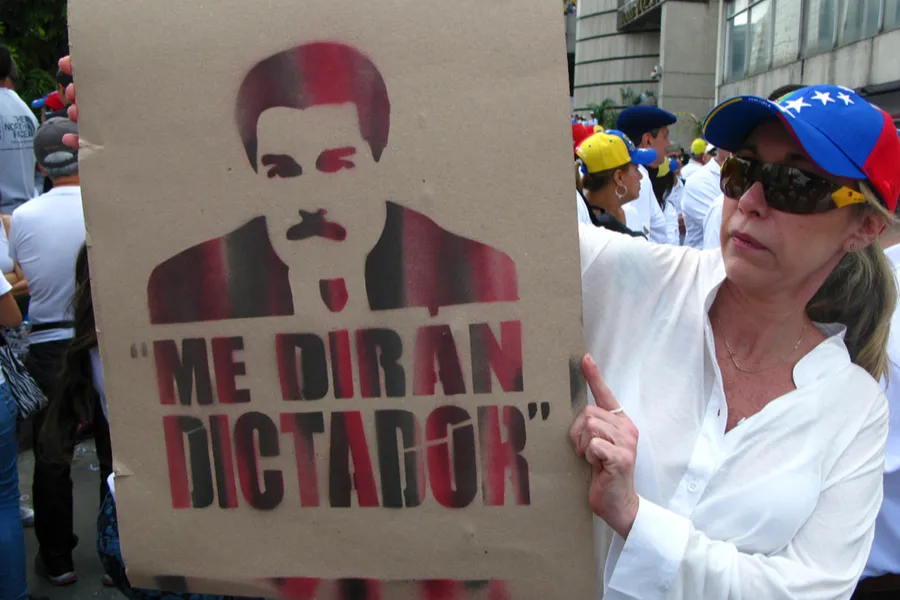 A woman holds a cartoon of Nicolas Maduro during opposition rally. ?w=200&h=150