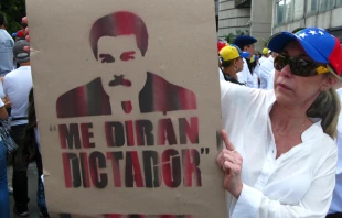 A woman holds a cartoon of Nicolas Maduro during opposition rally.   Edgloris Marys / Shutterstock