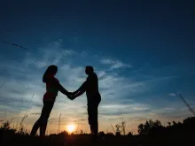 Couple holding hands at sunset. 
