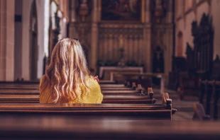 Woman alone in empty church.   encierro/Shutterstock