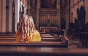Woman alone in empty church.   encierro/Shutterstock