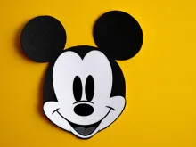 Black and white face of Mickey Mouse out of paper on a yellow background. 