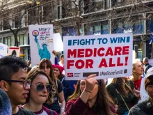 January 19, 2019 San Francisco / CA / USA - Participant to the Women's March event holds "Medicare for all" sign while marching on Market street in downtown San Francisco. 