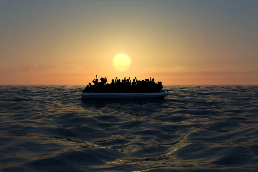 Refugees on a big rubber boat in the middle of the sea that require help. Via Shutterstock?w=200&h=150