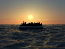 Refugees on a big rubber boat in the middle of the sea that require help. Via Shutterstock