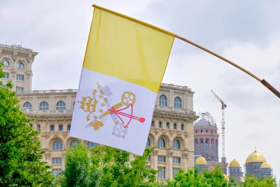 Flag of Vatican City on display in front of the Palace of Parliament in Bucharest, during Pope Francis 2019 visit in Romania. Via Shutterstock?w=200&h=150