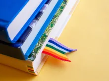 Stack of three books with rainbow ribbon bookmark. 