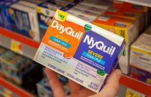 A man holds a box of Vicks DayQuil and NyQuil acetaminophen pills at Walmart in Albuquerque, New Mexico Nov. 2, 2020.   Giovanni Nastukov/Shutterstock.