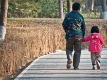 An elderly Chinese woman walks with her granddaughter.