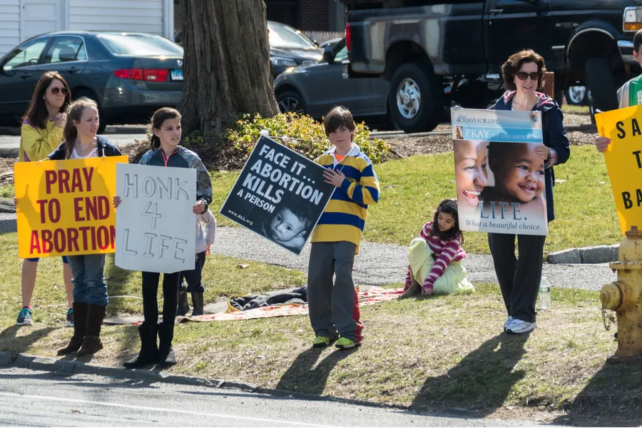  Adult and young people hold signs protesting abortion. ?w=200&h=150