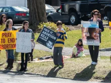  Adult and young people hold signs protesting abortion. 