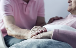Senior man holding hand of his ill wife.   Shutterstock