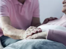 Senior man holding hand of his ill wife. 
