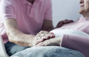 Senior man holding hand of his ill wife.   Shutterstock