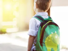 Child with schoolbag at home. 