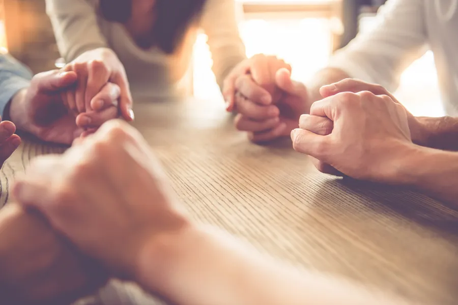 Women holding hands in prayer. Stock image via Shutterstock.?w=200&h=150