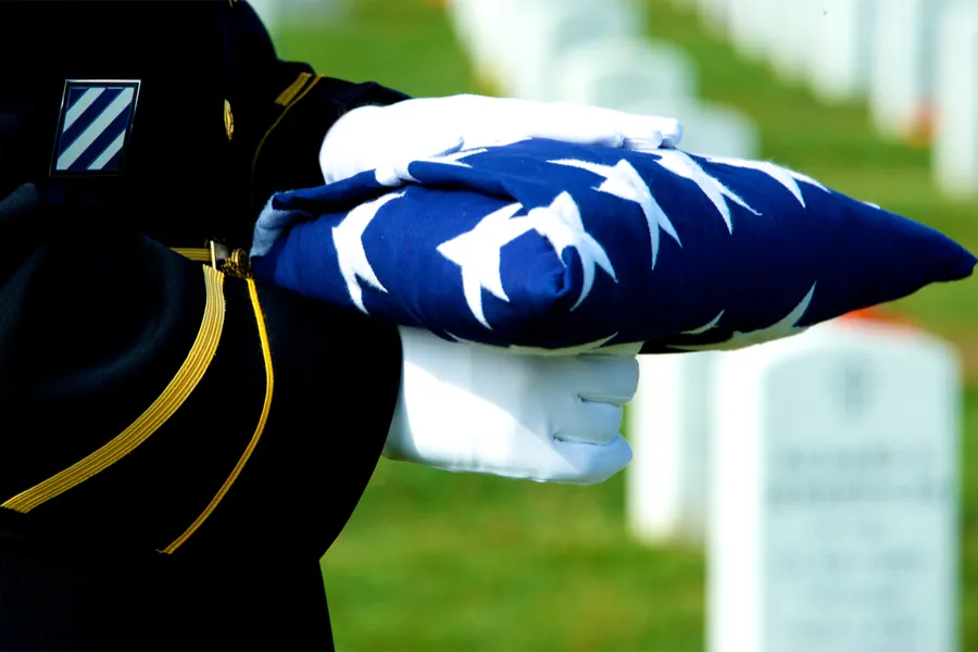 Honor Guard holding folded American flag at grave site at Arlington National Cemetery. Stock photo via Shutterstock?w=200&h=150