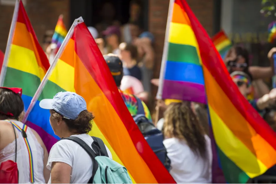 People with rainbows flags in the annual Pride Parade as it passes through Greenwich Village. Via Shutterstock.?w=200&h=150