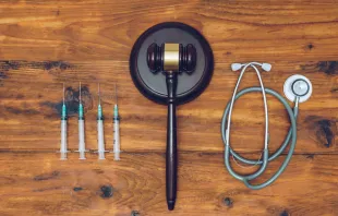 Syringes, stethoscope and judge gavel on wooden background.   sianstock/Shutterstock