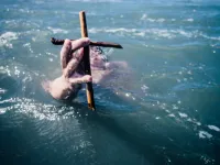 Man holding cross outside of water  / 