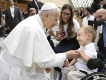 Pope Leo XIV greets sick and disabled people, including a young child in a wheelchair, in the Vatican’s Paul VI Hall after the Wednesday general audience on Sept. 10, 2025.