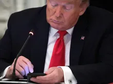  U.S. President Donald Trump works on his phone during a roundtable at the State Dining Room of the White House June 18, 2020 in Washington, DC. 