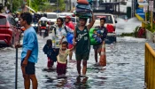 Residents carrying their belongings, wade through a flooded street in Mandaue City, Cebu province on Nov. 4, 2025, after Typhoon Kalmaegi hit overnight.