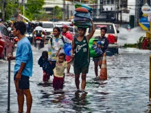 Residents carrying their belongings, wade through a flooded street in Mandaue City, Cebu province on Nov. 4, 2025, after Typhoon Kalmaegi hit overnight.