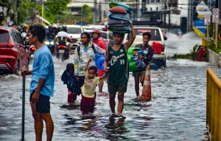 Residents carrying their belongings, wade through a flooded street in Mandaue City, Cebu province on Nov. 4, 2025, after Typhoon Kalmaegi hit overnight. Credit: Alan Tangcawan/AFP via Getty Images