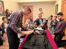 A young man touches a religious statue to the body of Sister Wilhelmina Lancaster, OSB, on May 18, 2023, at the Benedictines of Mary, Queen of Apostles monastery in Gower, Missouri.