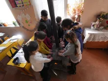Children warming their hands over a wood-fired oven in Nagorno-Karabakh