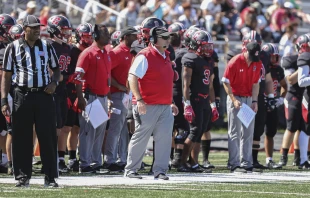 Mike Gutelius (center), head football coach of The Catholic University of America, watches the action on the sidelines. The Catholic University of America