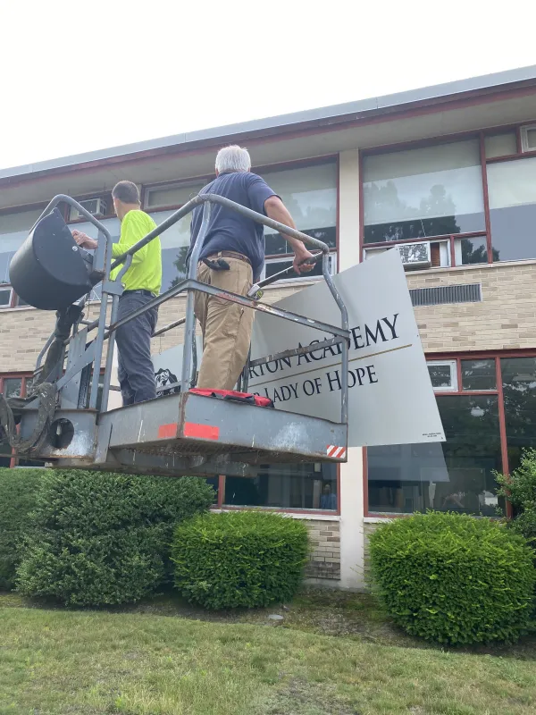 Volunteers help install a sign at Chesterton Academy of Our Lady of Hope. Credit: Chesterton Academy of Our Lady of Hope