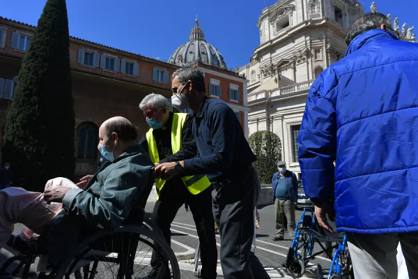 Cardinal Konrad Krajewski, dressed in a yellow vest, brings a disabled man to receive the vaccine against COVID-19 in the Vatican on March 31, 2021. Credit: Vatican Media.