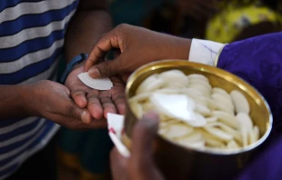 A priest distributes Holy Communion. Noah Seelam/AFP via Getty Images