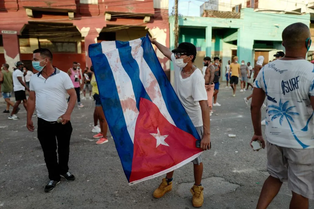 A man waves a Cuban flag during a demonstration against the government of Cuban President Miguel Diaz-Canel in Havana, July 11, 2021. - Thousands of Cubans took part in rare protests Sunday against the communist government, marching through a town chanting "Down with the dictatorship" and "We want liberty." Credit: Adalberto Roque/AFP via Getty Images.?w=200&h=150