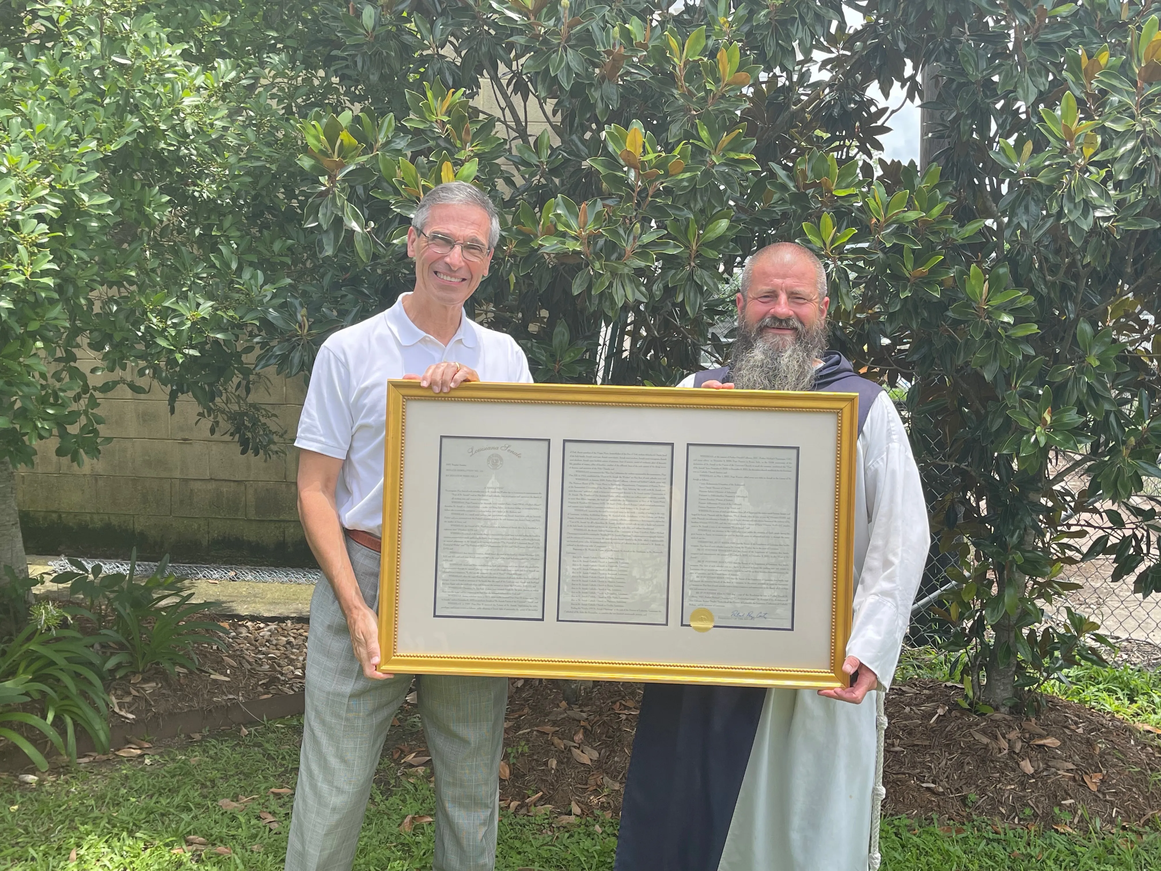 Louisiana Senator Fred Mills standing with Fr. Michael Champagne holding a framed copy of Senate Resolution No. 116. Credit: Jennifer Angelle.?w=200&h=150